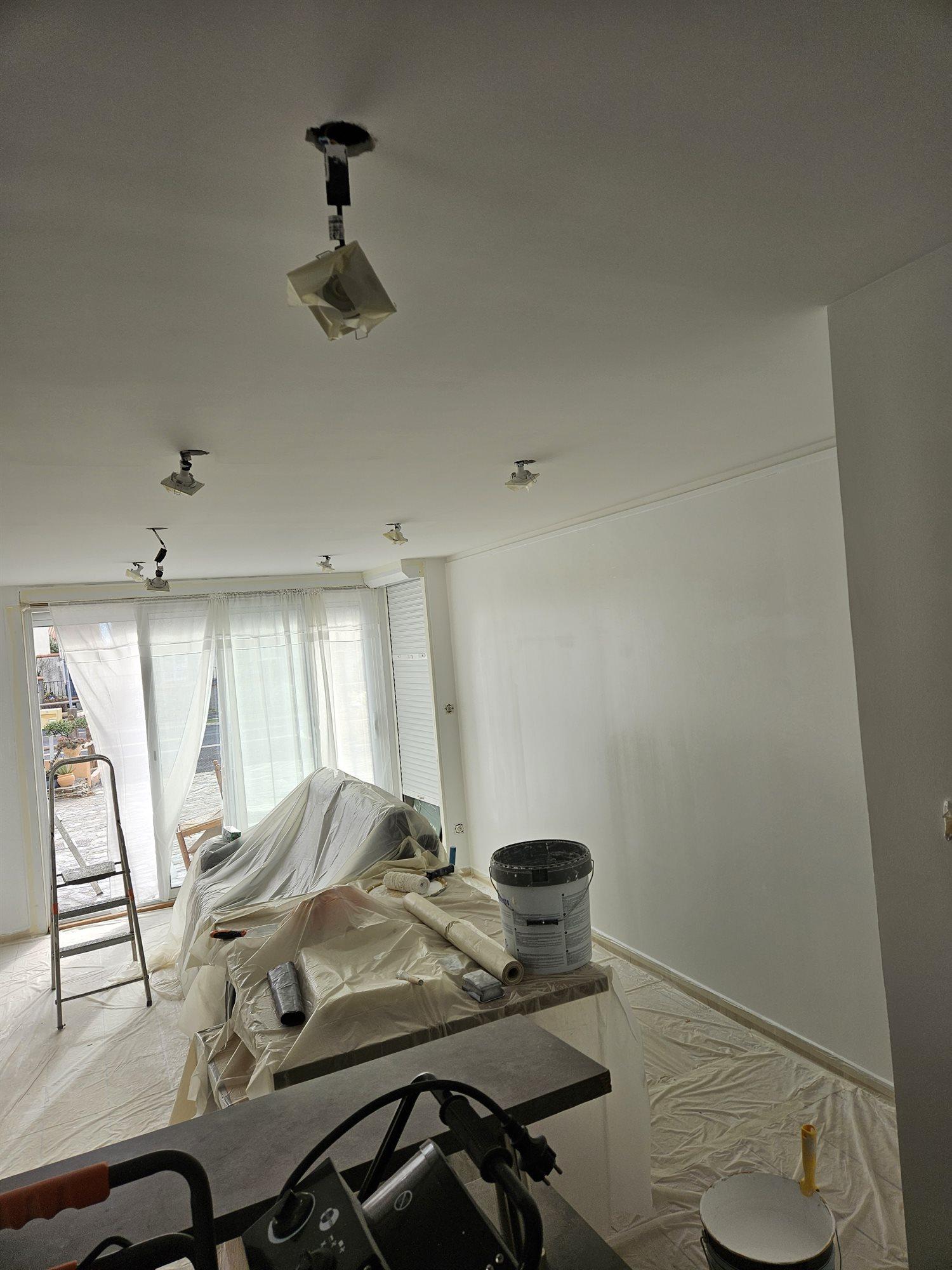 Séjour en cours de mise en peinture, mobilier bâché, sol protégé et spots démontés puis emballés